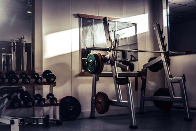 A simple workout notebook with handwritten strength numbers next to dumbbells and a protein shake, representing the power of basic training principles.