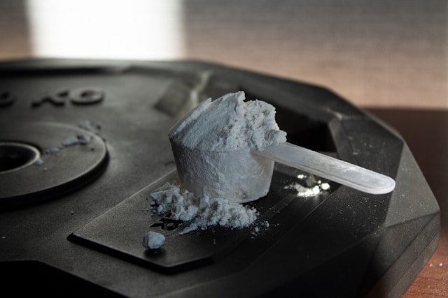 Three scoops of protein powder labeled whey, plant, and collagen next to a notebook and gym equipment, representing how to choose the right protein for your fitness goals.