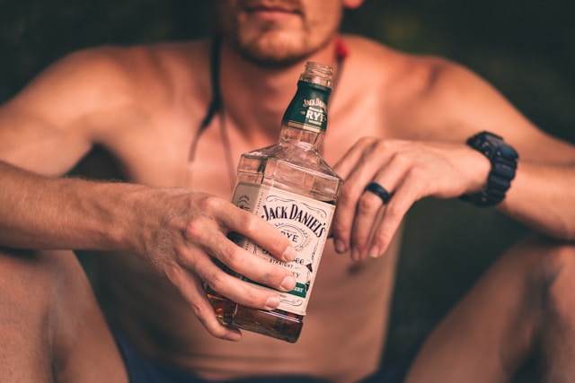 Man holding a beer with a disappointed expression, representing how alcohol sabotages fitness results.