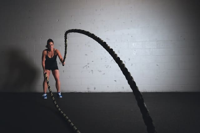 Woman performing a battle-rope HIIT workout in a gym