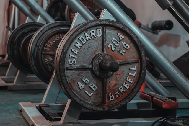 A vintage cast iron barbell in a rustic gym setting, representing old‑school strength training principles that still build real muscle today.