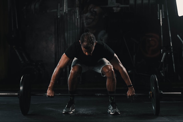A fit man in his 40s performing a squat in a gym, representing strength training to reverse age‑related muscle loss and burn fat.