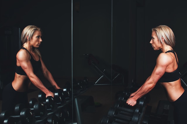 Woman strength training after 40 with dumbbells in a gym for joint-friendly muscle building.