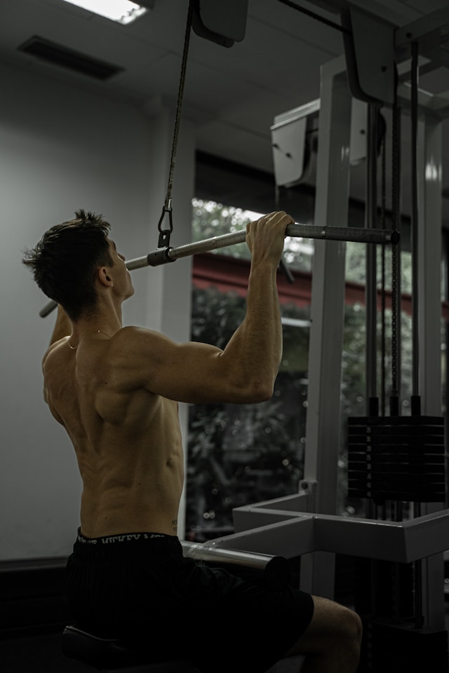 Man training back muscles with a lat pulldown for strength, trunk muscle quality, and heart health.